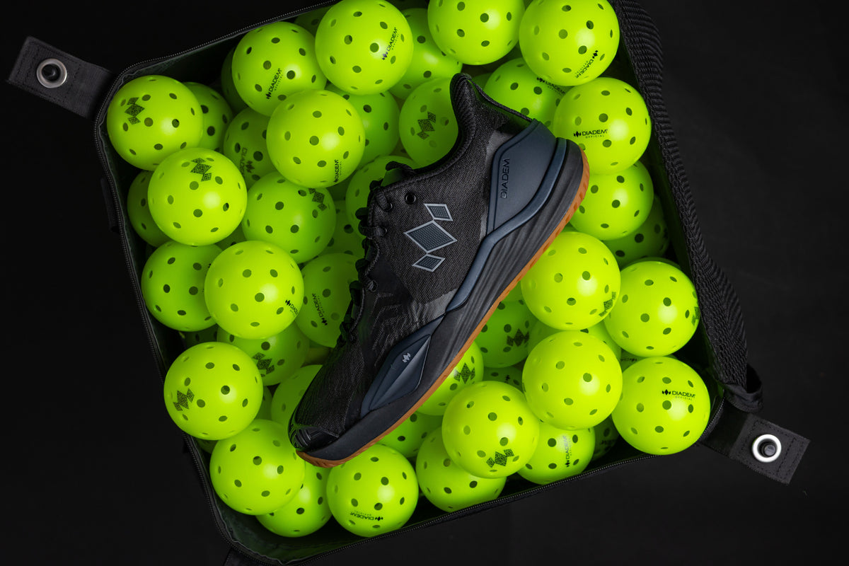 Black sports shoe surrounded by bright green balls in a black container.
