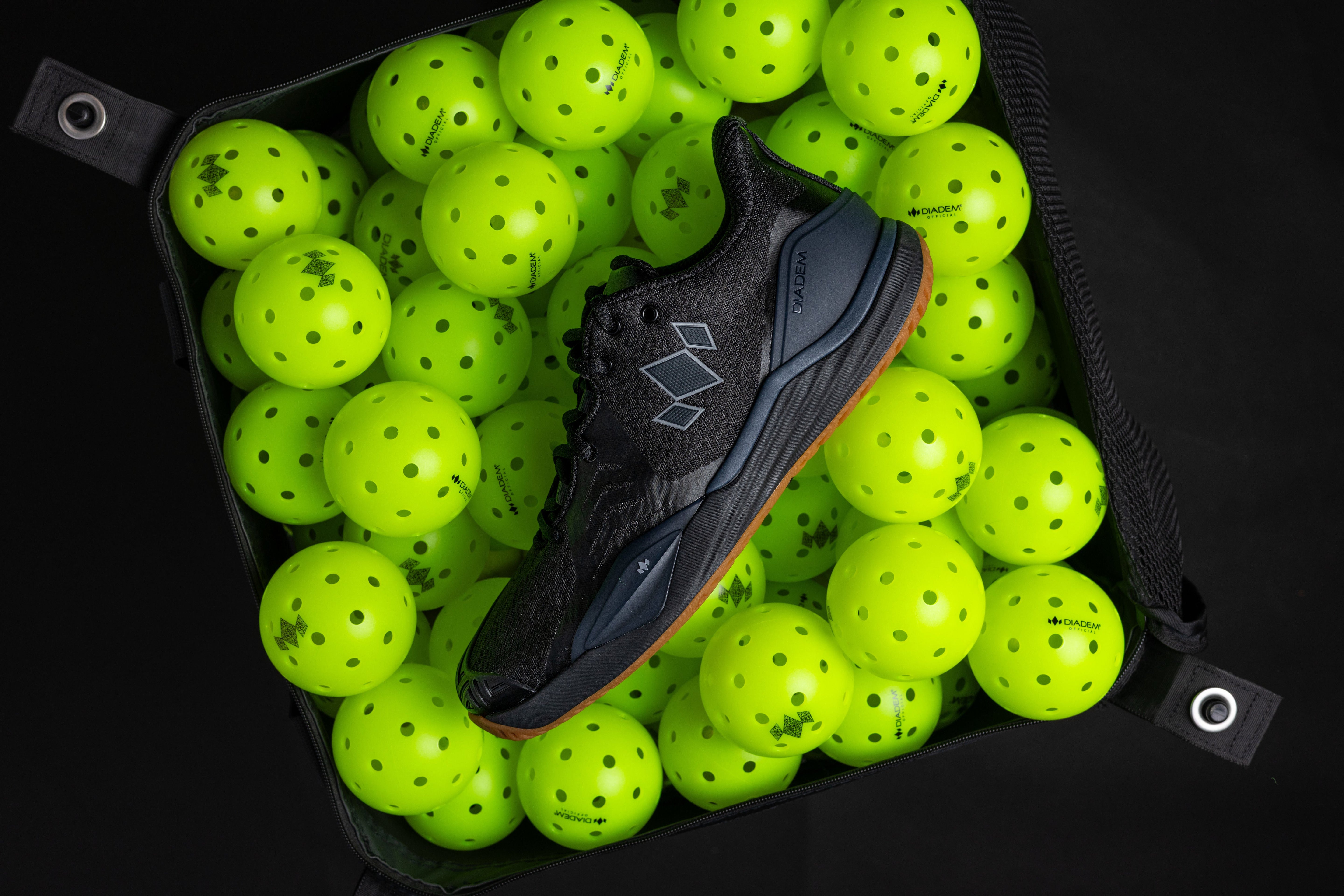 Black sports shoe surrounded by bright green balls in a black container.