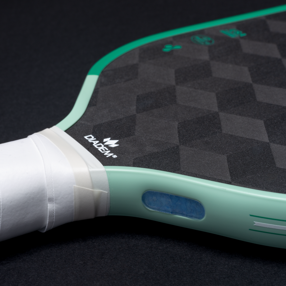 Close-up of a pickleball paddle with a checkered pattern on a black background