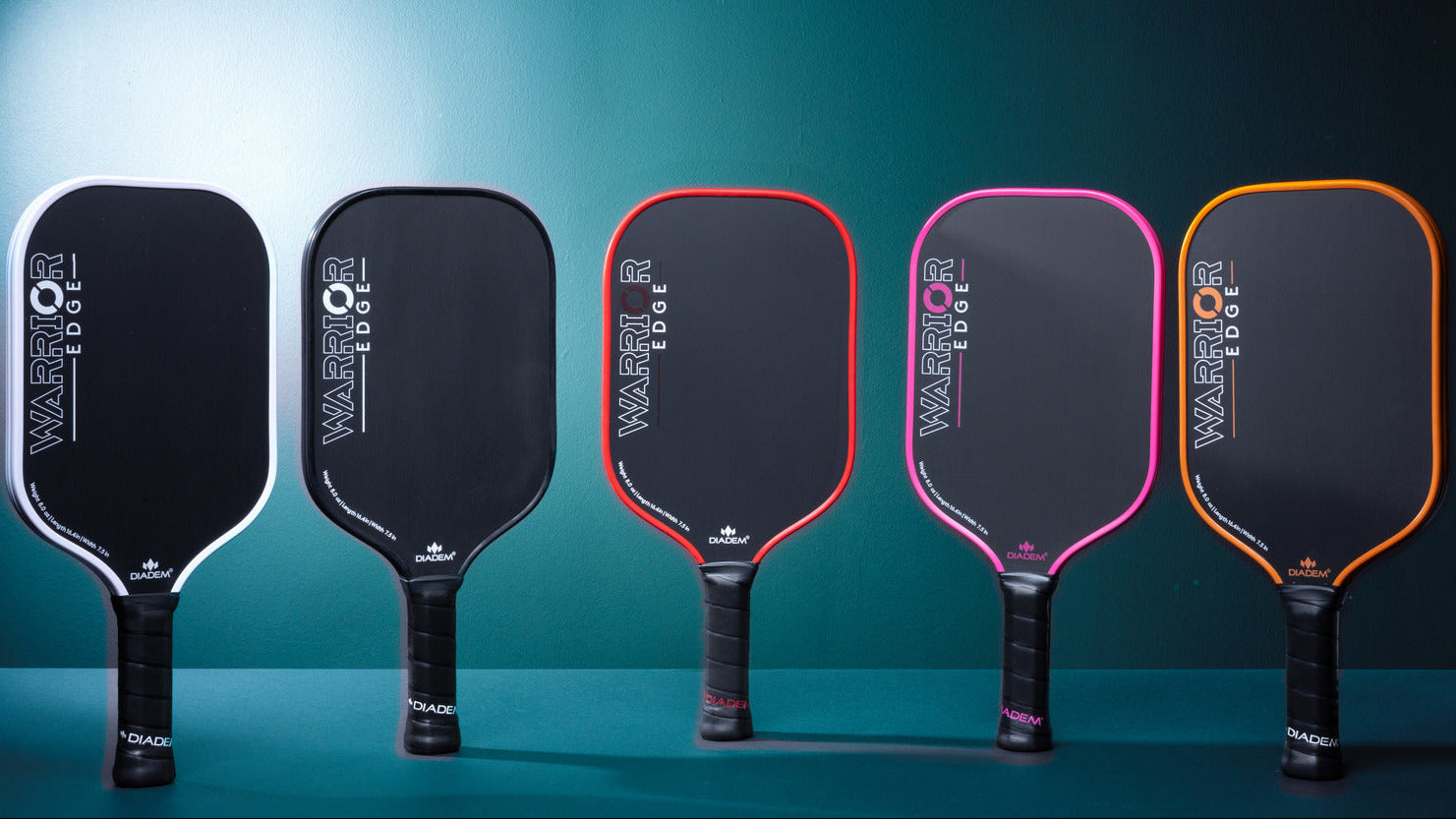 Five Warrior pickleball paddles in various colors on a blue background